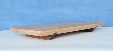 This beech and walnut Charcuterie / Cheese Board floats on air.  All bevelling and shaping has been done with handsaws and hand planes.&nbsp;  Its walnut feet keep its surface raised and allow easy transfer from the kitchen to the table as well as easy pick-up when serving your guests.&nbsp;  Finished with a food safe orange wax.  H57 x W292 x L548mm  Handmade in Dublin, Ireland&nbsp;